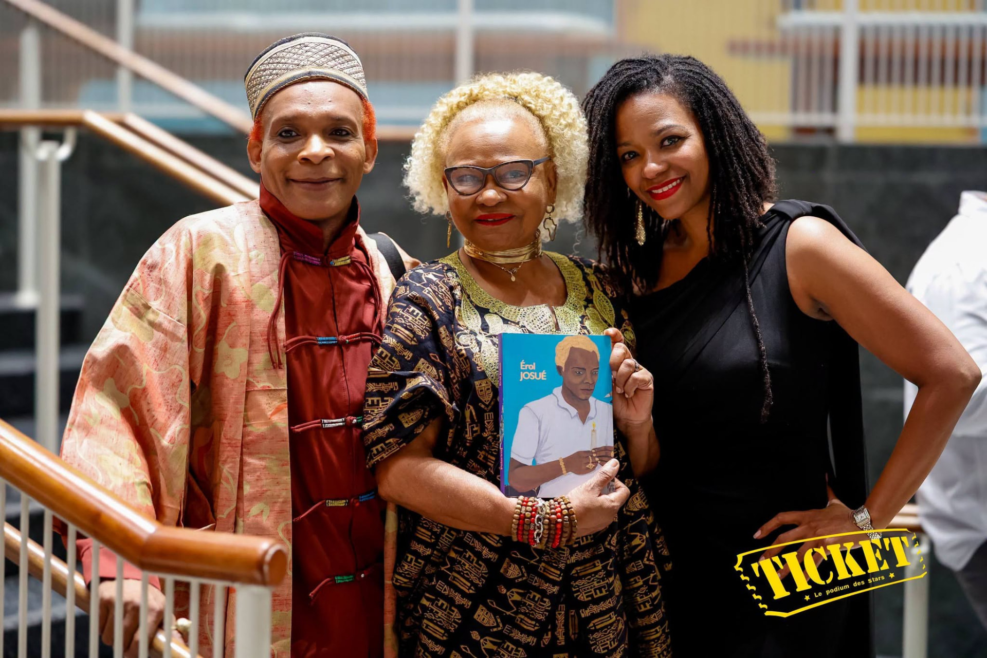 Érol Josué with two guests holding his book